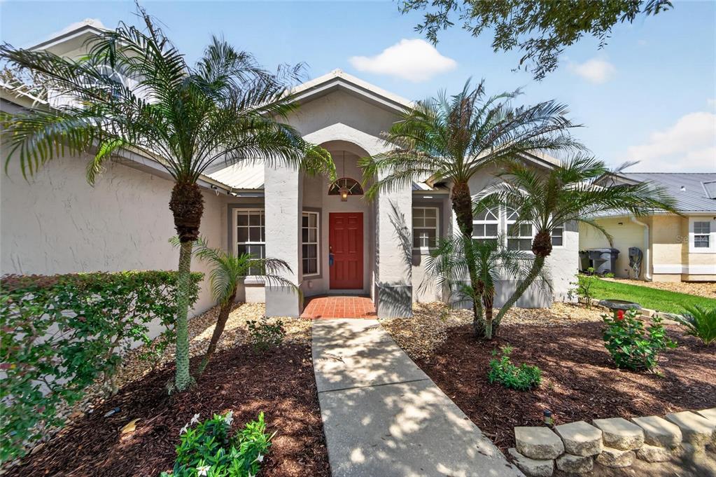 A single-story house with a red front door, palm trees, and a concrete walkway — 5309 ST LUCIA DRIVE, LAKELAND, FL