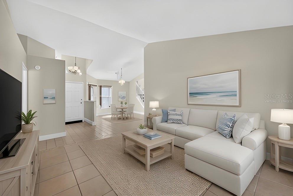 A virtually staged living room features a white sectional sofa, coffee table, and tile flooring — 5309 ST LUCIA DRIVE, LAKELAND, FL