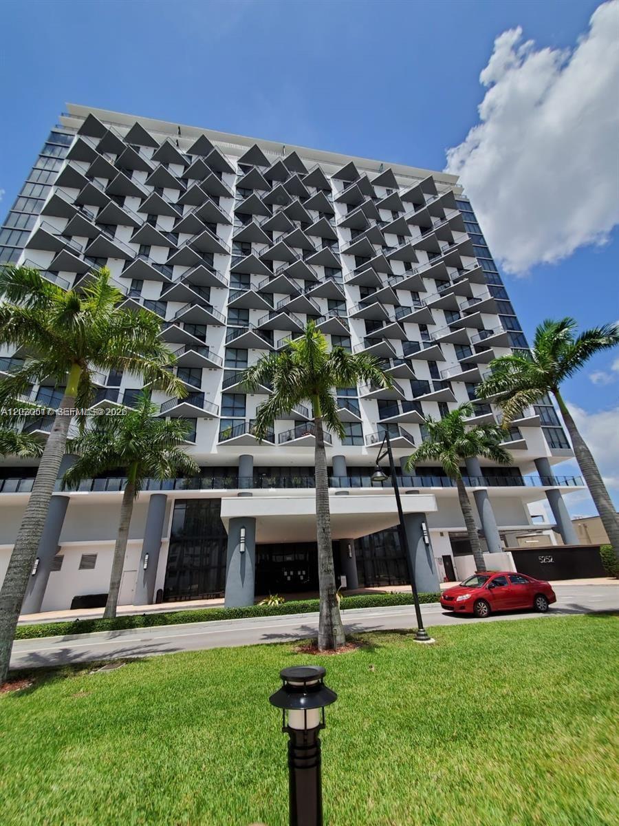 A modern high-rise apartment building features prominent triangular balconies and a red car parked outside — 5252 NW 85th Ave # 1104, Doral FL 33166, DORAL, FL