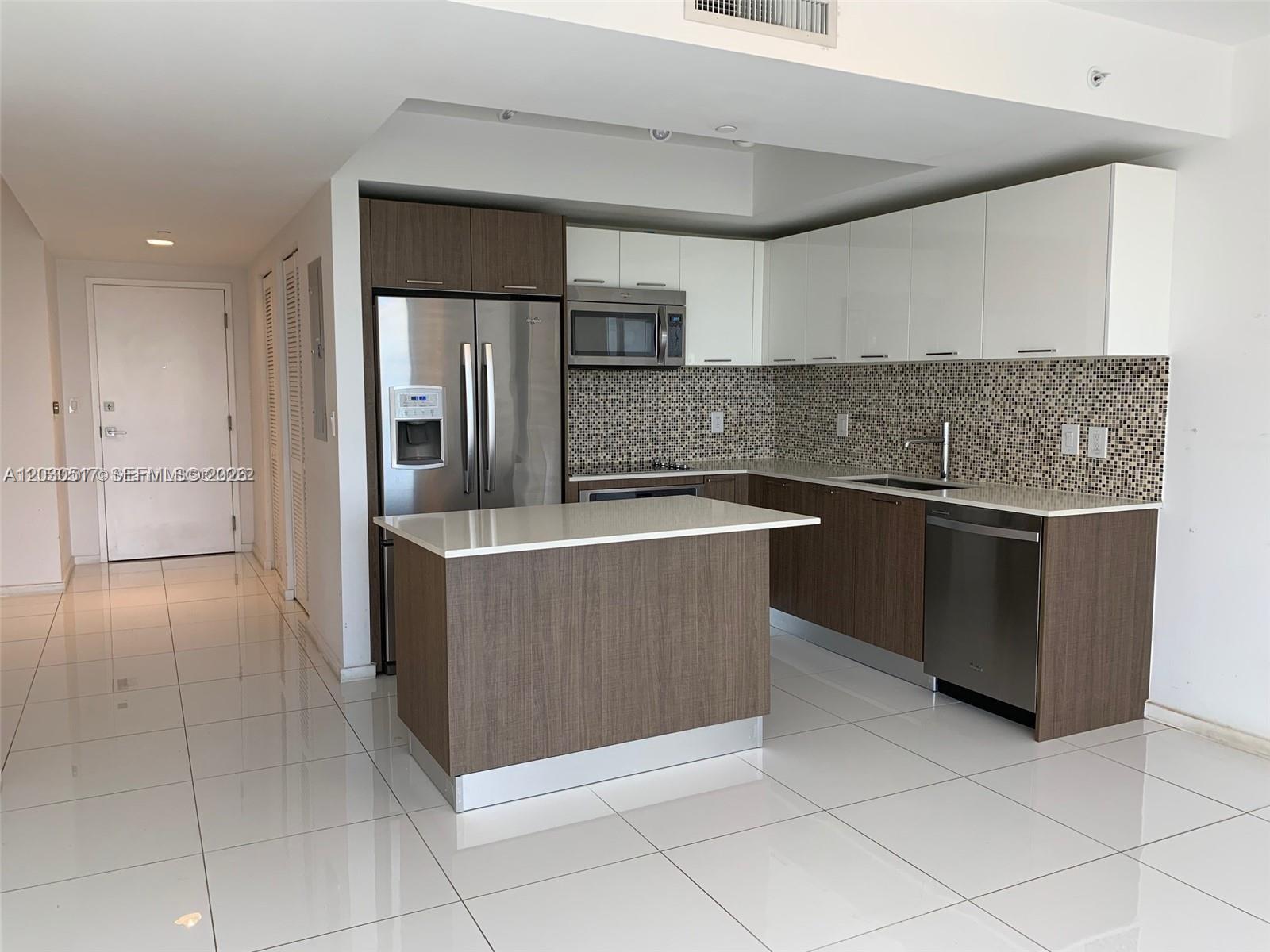 A modern kitchen features two-toned cabinetry, stainless steel appliances, and a white quartz island — 5252 NW 85th Ave # 1104, Doral FL 33166, DORAL, FL
