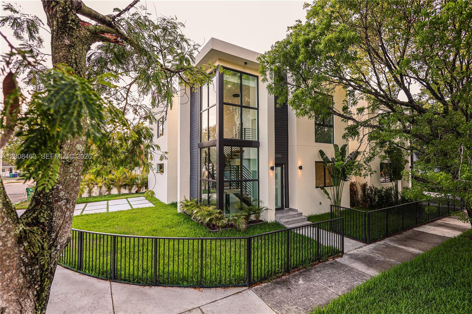A modern two-story house features a glass-enclosed staircase, white stucco walls, and a black fence — 5800 NW 5th Ave #5800, Miami FL 33127, MIAMI, FL
