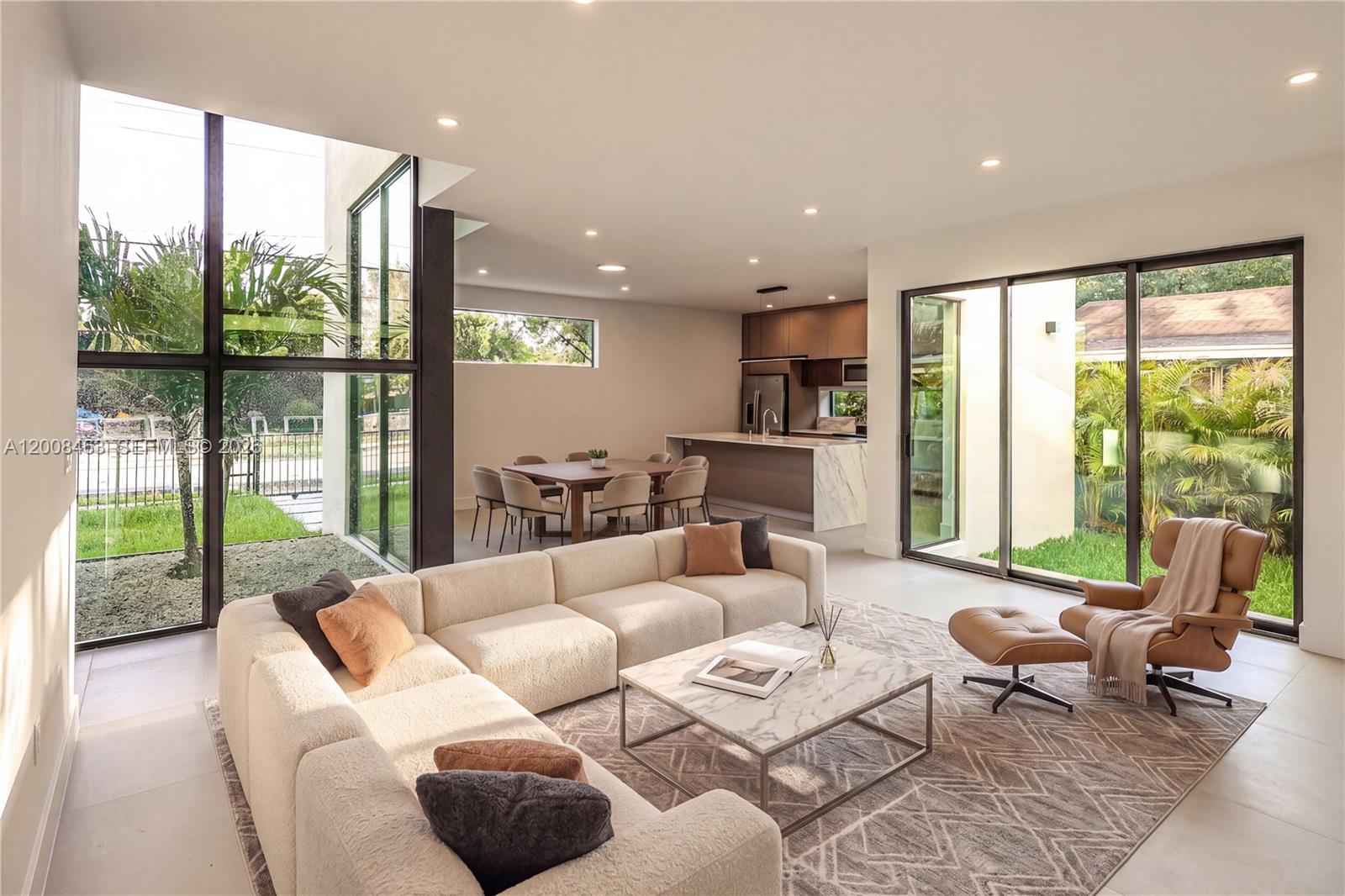 A modern open-concept living and dining area features a large sectional, marble coffee table, and floor-to-ceiling windows — 5800 NW 5th Ave #5800, Miami FL 33127, MIAMI, FL