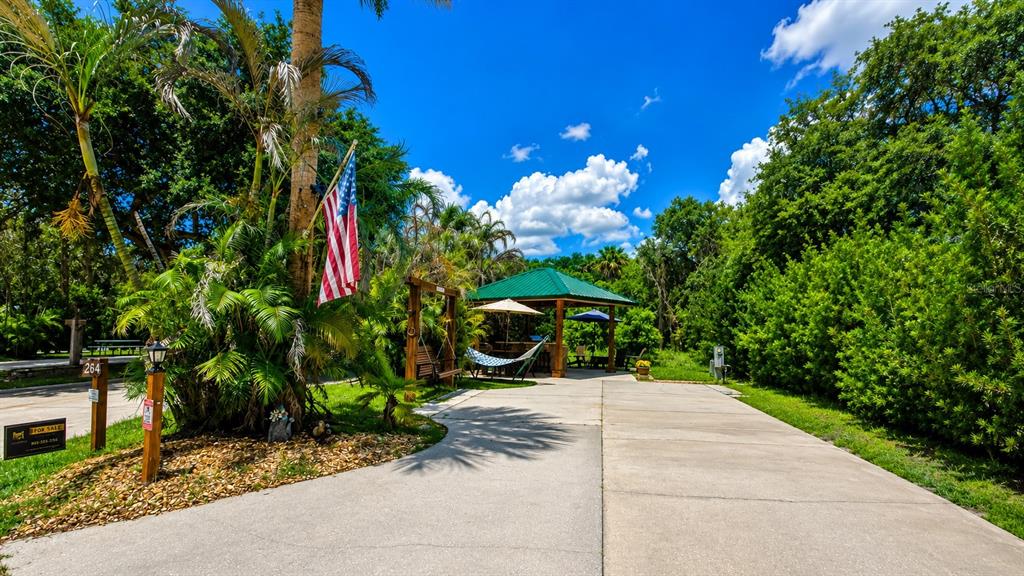 A paved driveway leads to a covered outdoor pavilion with a hammock and patio furniture — 264 SADDLE LANE, RIVER RANCH, FL
