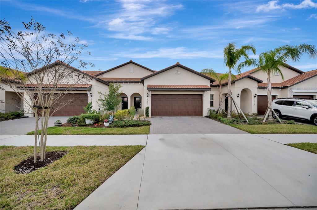 A row of attached single-story houses with brown garage doors and tile roofs — 17436 HOLLY WELL AVENUE, WIMAUMA, FL