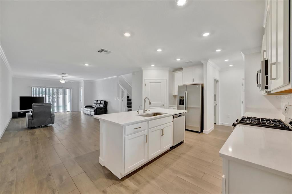 A kitchen with white cabinets and a center island opens into a spacious living area — 17436 HOLLY WELL AVENUE, WIMAUMA, FL