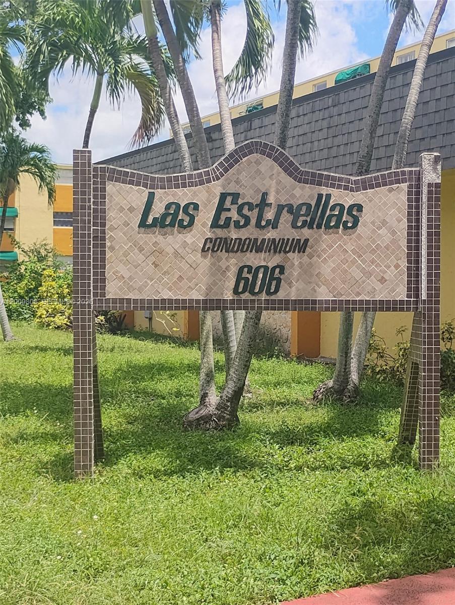 A sign for Las Estrellas Condominium stands in a grassy area with palm trees — 606 W 81st St # 309, Hialeah FL 33014, HIALEAH, FL