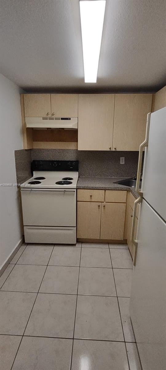 A kitchen features light wood cabinets, white appliances, a gray countertop, and tiled flooring — 606 W 81st St # 309, Hialeah FL 33014, HIALEAH, FL