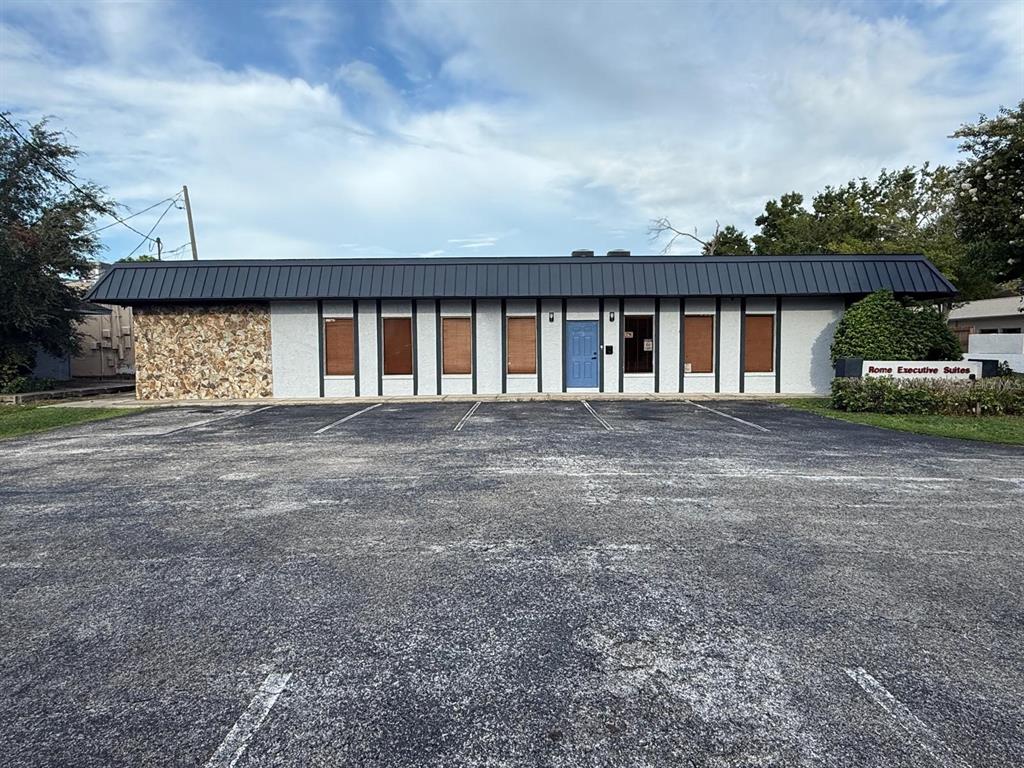 A single-story commercial building with a stone facade, dark metal roof, and parking lot — 13506 N ROME AVENUE, TAMPA, FL