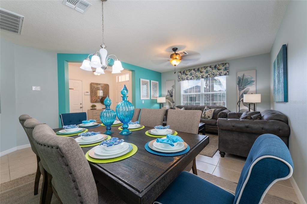 A dining room with a dark wood table, blue chairs, and an adjacent living area — 1355 YORKSHIRE COURT, DAVENPORT, FL
