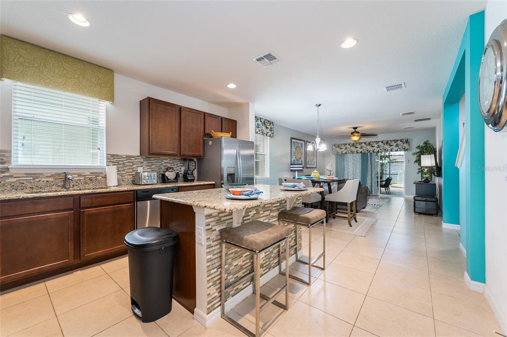 A kitchen with dark wood cabinets, granite countertops, and a breakfast bar island — 1355 YORKSHIRE COURT, DAVENPORT, FL