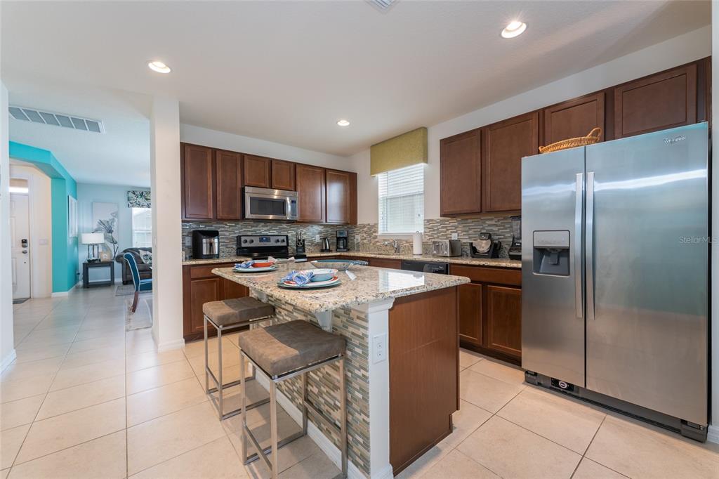 A kitchen with dark wood cabinets, granite countertops, a center island, and stainless steel appliances — 1355 YORKSHIRE COURT, DAVENPORT, FL