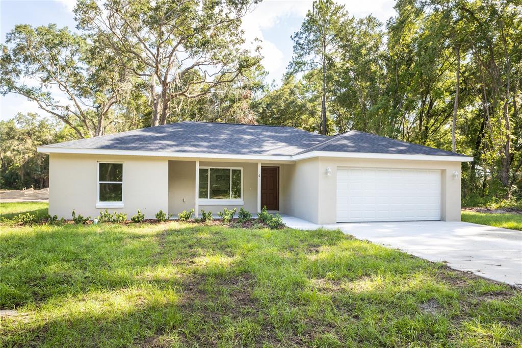 A single-story house with a beige stucco exterior, a dark roof, and a two-car garage — 1057 NW TIMBERLAKE ROAD, DUNNELLON, FL