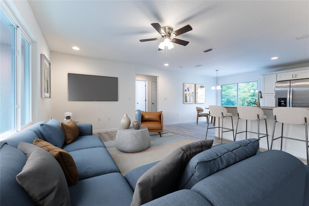 A living room with a blue sectional sofa, a round coffee table, and an open kitchen — 1057 NW TIMBERLAKE ROAD, DUNNELLON, FL