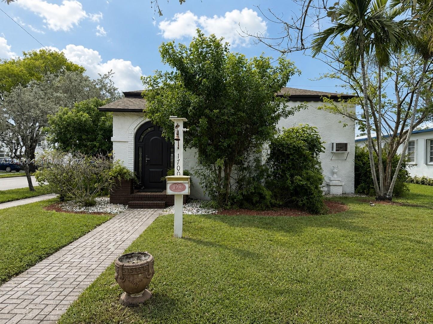 A white stucco house with a dark arched front door and a brick walkway — 1700 Dewey St, Hollywood FL 33020, HOLLYWOOD, FL