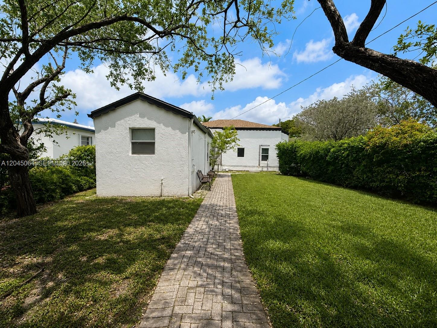 A white detached building sits beside a brick walkway leading to a larger house — 1700 Dewey St, Hollywood FL 33020, HOLLYWOOD, FL