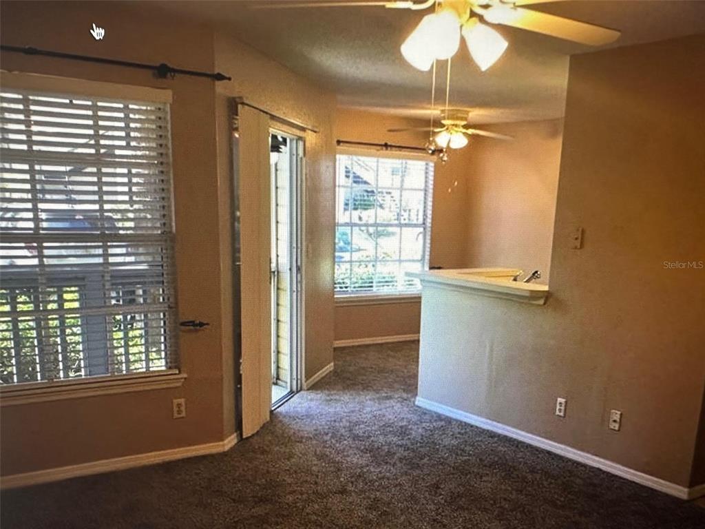 A carpeted room features a ceiling fan, a sliding glass door, and a half wall — 1071 S HIAWASSEE ROAD UNIT 1213, ORLANDO, FL