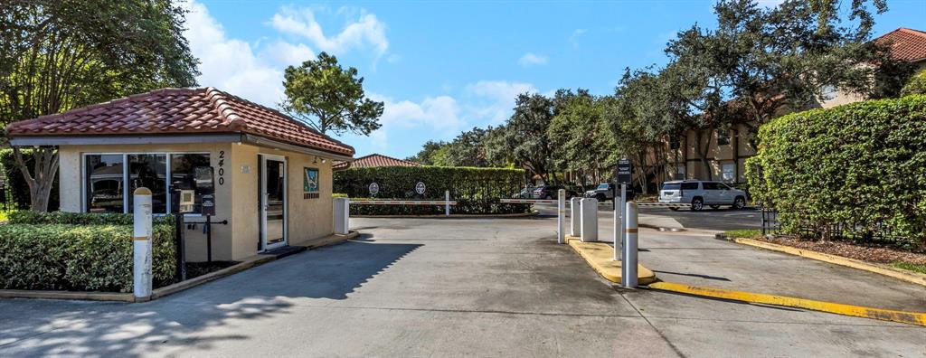 A gated entrance features a guardhouse with a tiled roof and a vehicle barrier arm — 2400 FEATHER SOUND DRIVE UNIT 412, CLEARWATER, FL