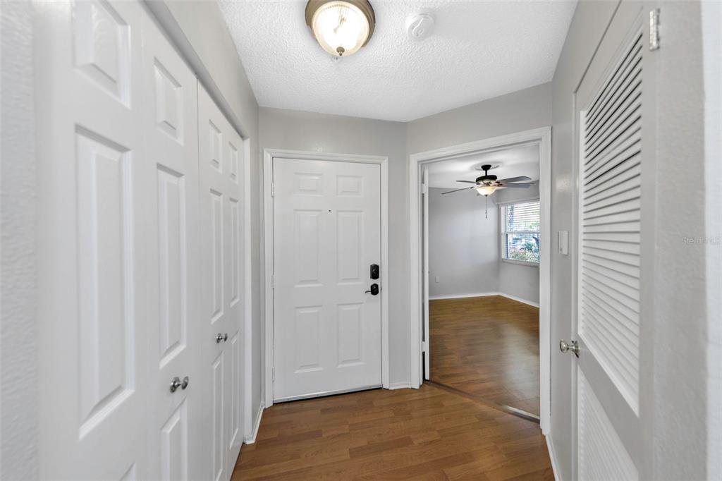 An entryway features white doors, wood-look flooring, and a view into an adjacent room — 2400 FEATHER SOUND DRIVE UNIT 412, CLEARWATER, FL