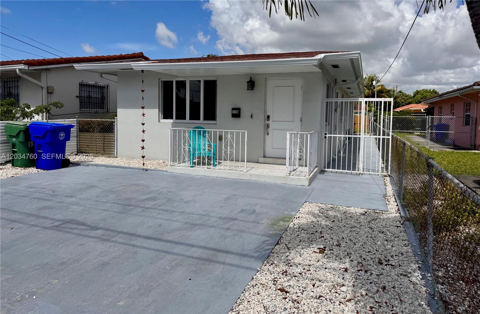 A single-story house with a gray concrete driveway, white metal railings, and a front door — 1158 NW 34th Ave # 1, Miami FL 33125, MIAMI, FL