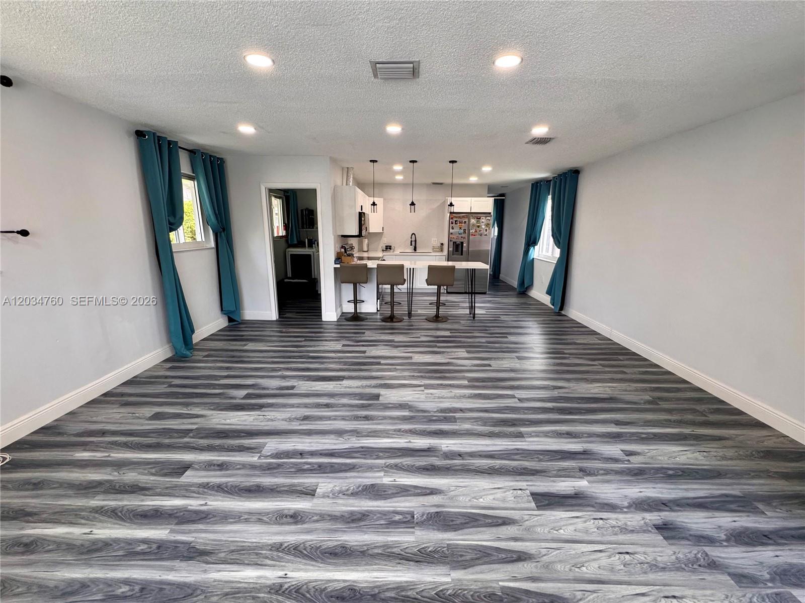 An open-concept living area features gray wood-look flooring, recessed lighting, and a kitchen with bar seating — 1158 NW 34th Ave # 1, Miami FL 33125, MIAMI, FL