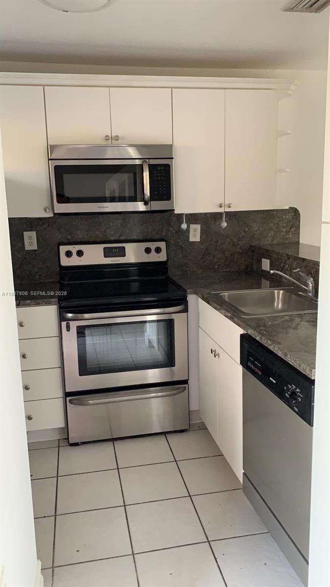 A kitchen features white cabinets, stainless steel appliances, and dark stone countertops — 7905 NW 8 ST # 8A, Miami FL 33126, MIAMI, FL