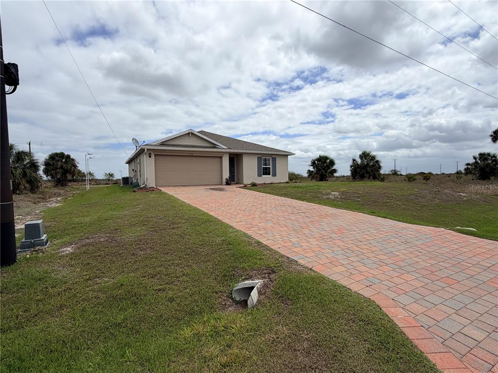 A single-story house with a beige exterior, a two-car garage, and a paved driveway — 513 ELLA JEAN PI, BANYAN VILLAGE, LABELLE, FL