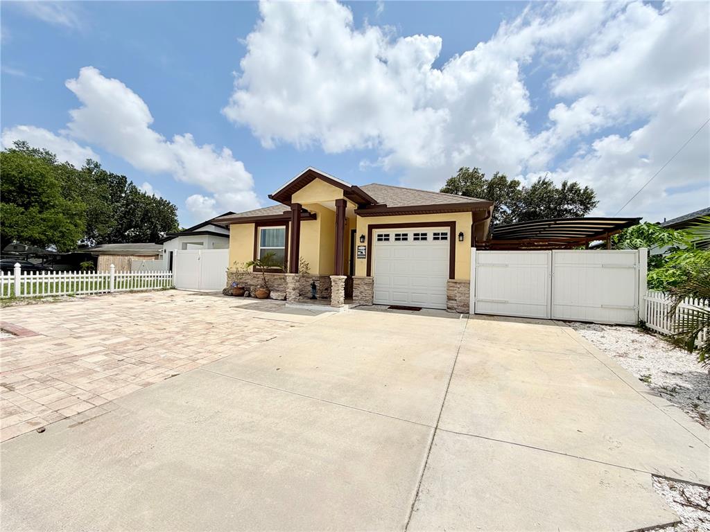A single-story house with a yellow exterior, stone accents, a garage, and a paved driveway — 5160 70TH AVENUE N, PINELLAS PARK, FL