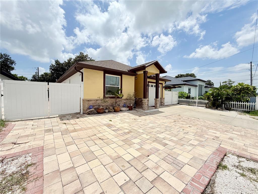 A yellow house with a stone facade and a large paved driveway — 5160 70TH AVENUE N, PINELLAS PARK, FL