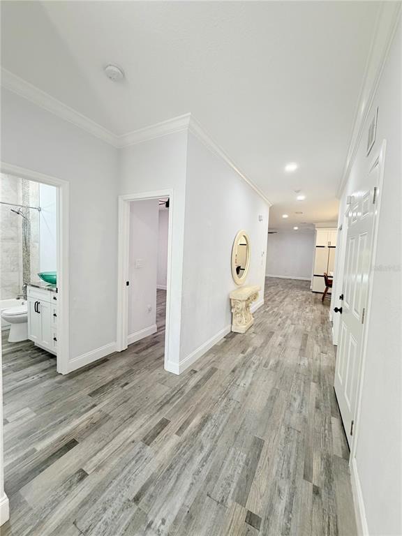 A hallway with wood-look flooring leads past a bathroom and bedroom toward a kitchen area — 5160 70TH AVENUE N, PINELLAS PARK, FL