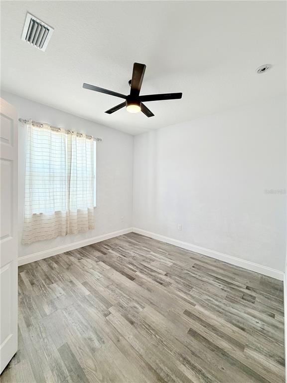 An empty bedroom features white walls, a ceiling fan, and light-colored wood-look flooring — 5160 70TH AVENUE N, PINELLAS PARK, FL