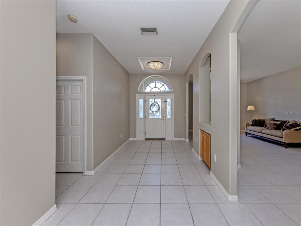 A tiled foyer leads to a front door with a transom window and a chandelier — 6511 WESTWARD PLACE, BRADENTON, FL