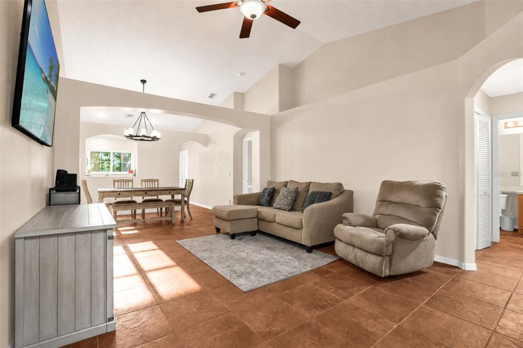 A living room with tile floors, a sectional sofa, a recliner, and an adjacent dining area — 2830 OSPREY COVE PLACE UNIT 203, KISSIMMEE, FL
