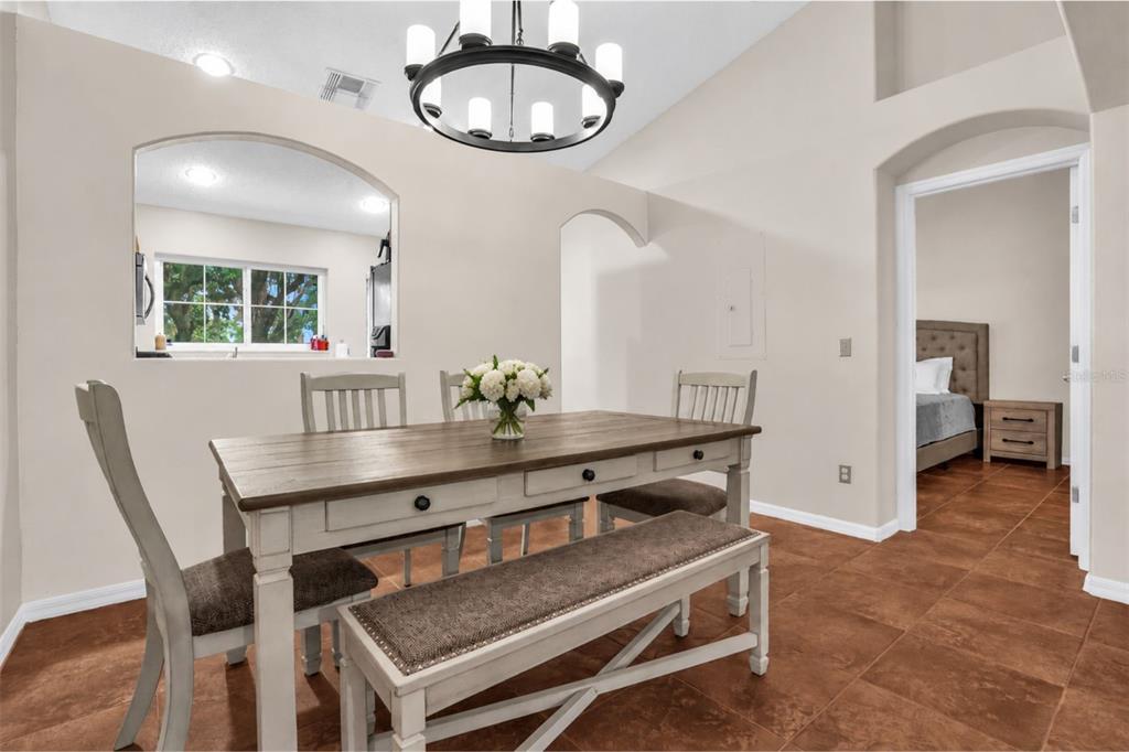 A dining area features a wooden table with a bench, chairs, and a chandelier — 2830 OSPREY COVE PLACE UNIT 203, KISSIMMEE, FL