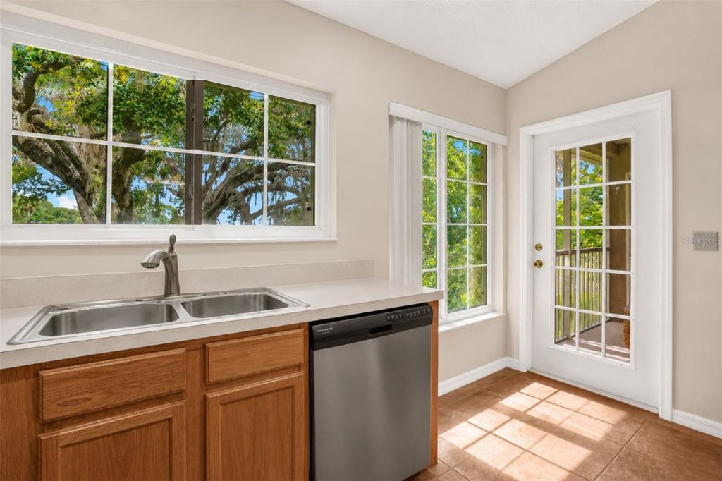 A kitchen features a stainless steel dishwasher, a double sink, and a glass-paneled exterior door — 2830 OSPREY COVE PLACE UNIT 203, KISSIMMEE, FL