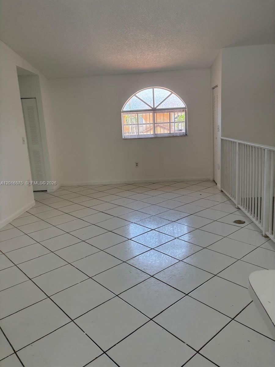 An empty room features white walls, a large arched window, and white tiled flooring — 7778 W 34th Ln # 201, Hialeah FL 33018, HIALEAH, FL