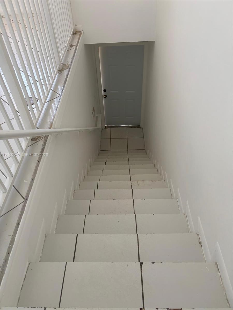 A staircase with white tiled steps leads down to a closed white door — 7778 W 34th Ln # 201, Hialeah FL 33018, HIALEAH, FL
