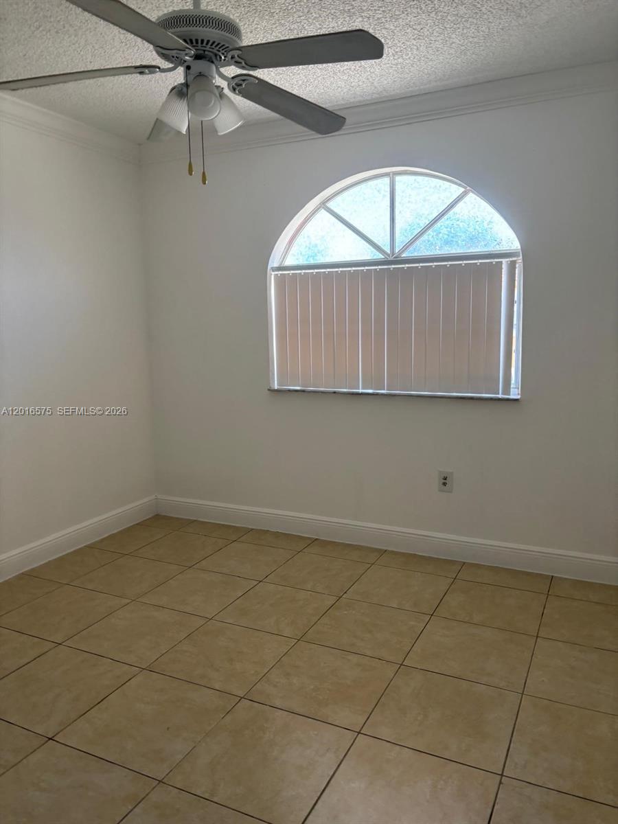 An empty room features white walls, beige tile flooring, a ceiling fan, and an arched window — 7778 W 34th Ln # 201, Hialeah FL 33018, HIALEAH, FL