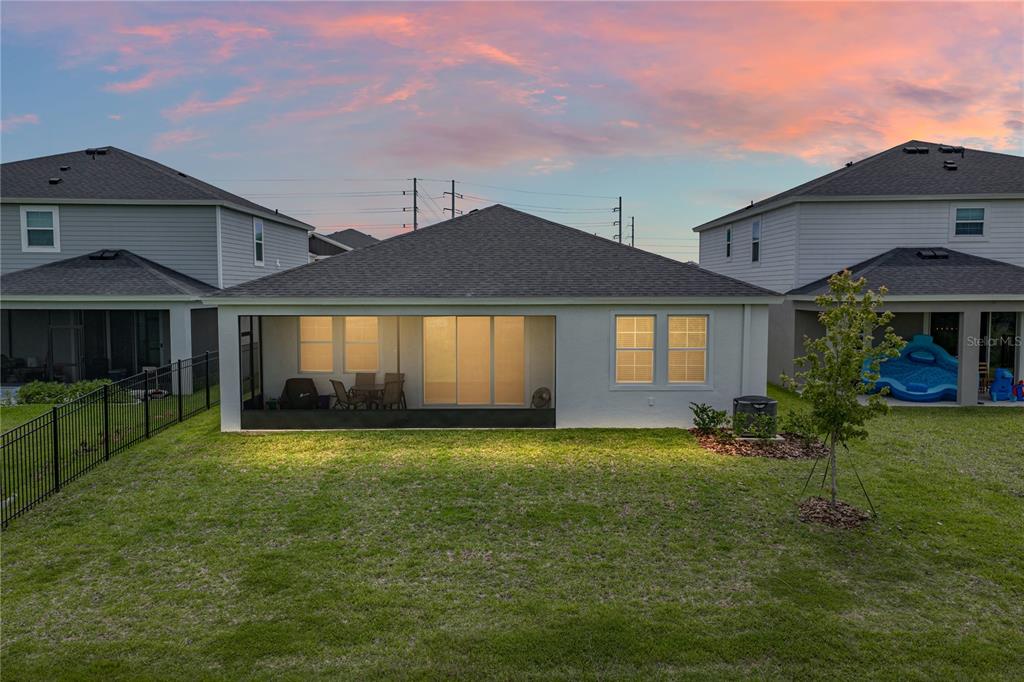 The exterior rear view of a single-story house features a screened-in patio and lawn — 12253 CATTLESIDE DRIVE, RIVERVIEW, FL