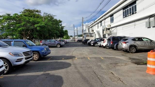 An outdoor parking lot with several vehicles parked alongside a white commercial building — 1 PR-1 INT. SAKURA ST., CAGUAS, PR