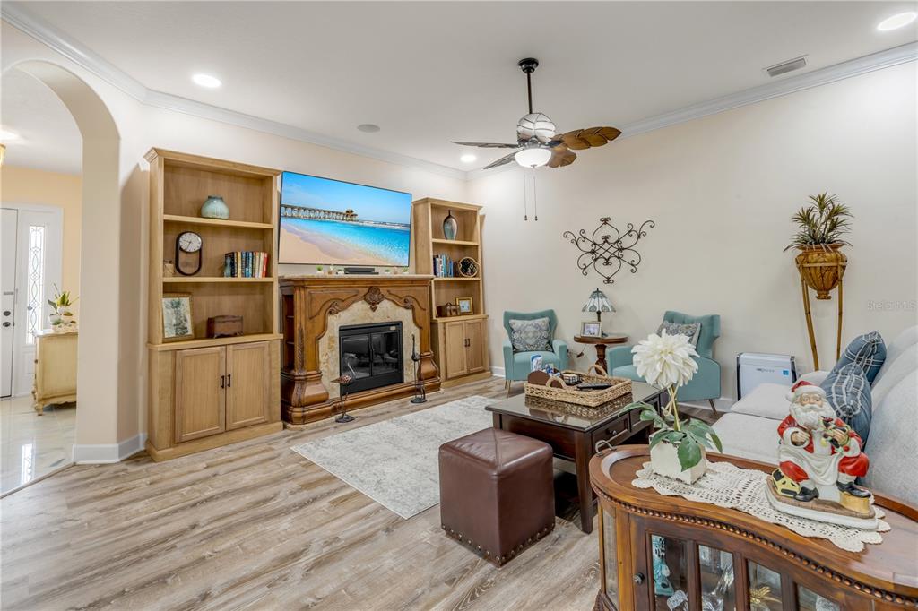 A living room features a fireplace, built-in shelving, a ceiling fan, and light wood flooring — 3364 TORRE BOULEVARD, NEW SMYRNA BEACH, FL