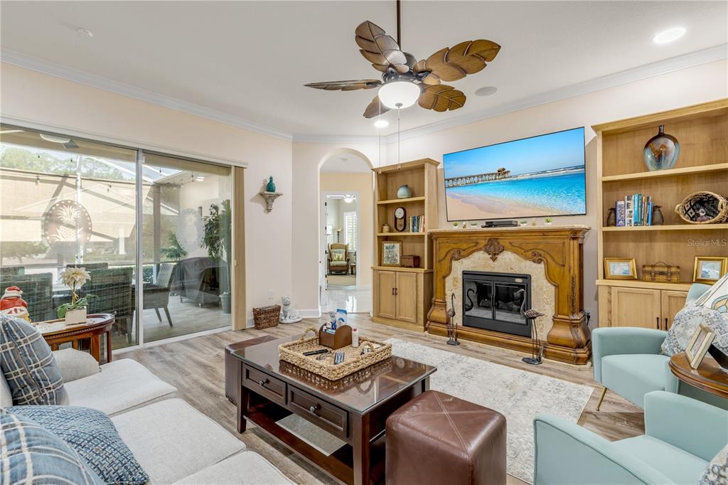 A living room features a fireplace, built-in shelving, a ceiling fan, and sliding glass doors — 3364 TORRE BOULEVARD, NEW SMYRNA BEACH, FL