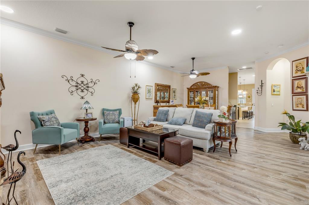 A living room features light-colored walls, wood-look flooring, a sofa, two armchairs, and ceiling fans — 3364 TORRE BOULEVARD, NEW SMYRNA BEACH, FL