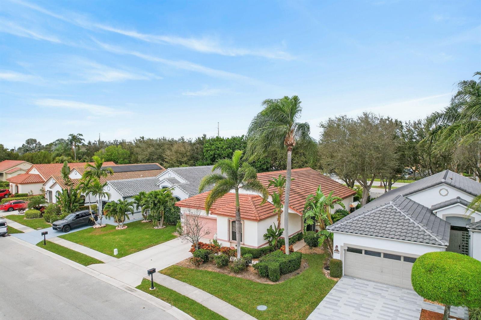 An aerial view shows several suburban houses with tiled roofs and palm trees along a street — 10056 Lexington Circle N, Boynton Beach FL 33436, BOYNTON BEACH, FL