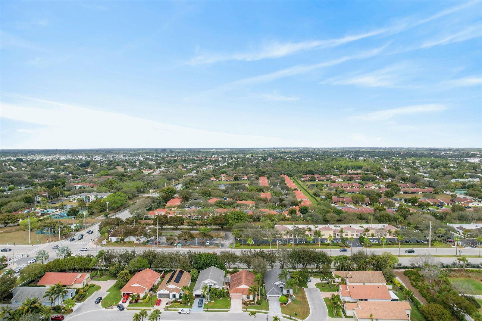 An aerial view shows a suburban neighborhood with houses, streets, and green trees under a sky — 10056 Lexington Circle N, Boynton Beach FL 33436, BOYNTON BEACH, FL