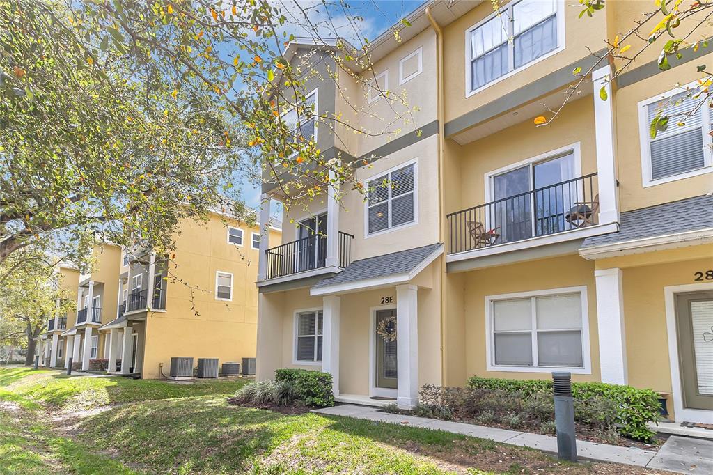 A three-story yellow townhouse exterior with balconies and a front entrance labeled 28E — 28 W ESTHER STREET UNIT E, ORLANDO, FL