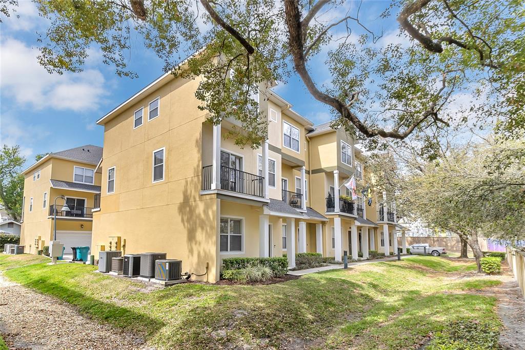 A multi-story yellow townhouse complex with balconies and exterior air conditioning units — 28 W ESTHER STREET UNIT E, ORLANDO, FL