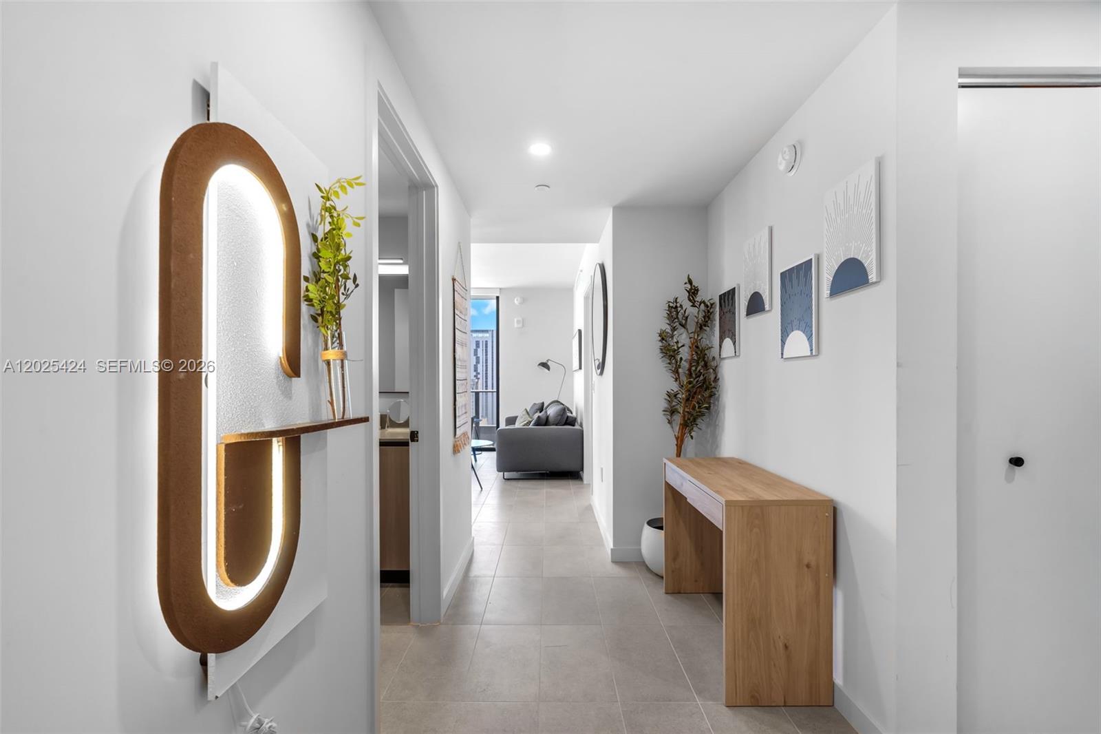 A hallway with light tile flooring leads to a living area with a sofa — 121 NE 5th St # 2301, Miami FL 33132, MIAMI, FL