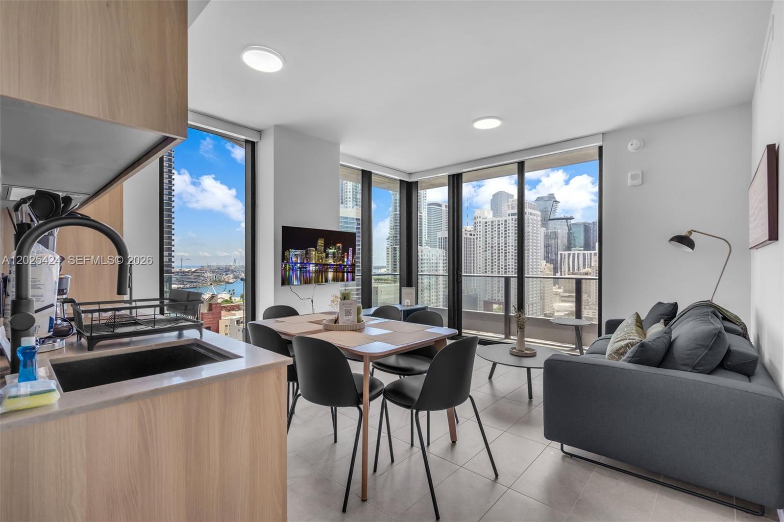 A modern apartment living and dining area features floor-to-ceiling windows with city skyline views — 121 NE 5th St # 2301, Miami FL 33132, MIAMI, FL