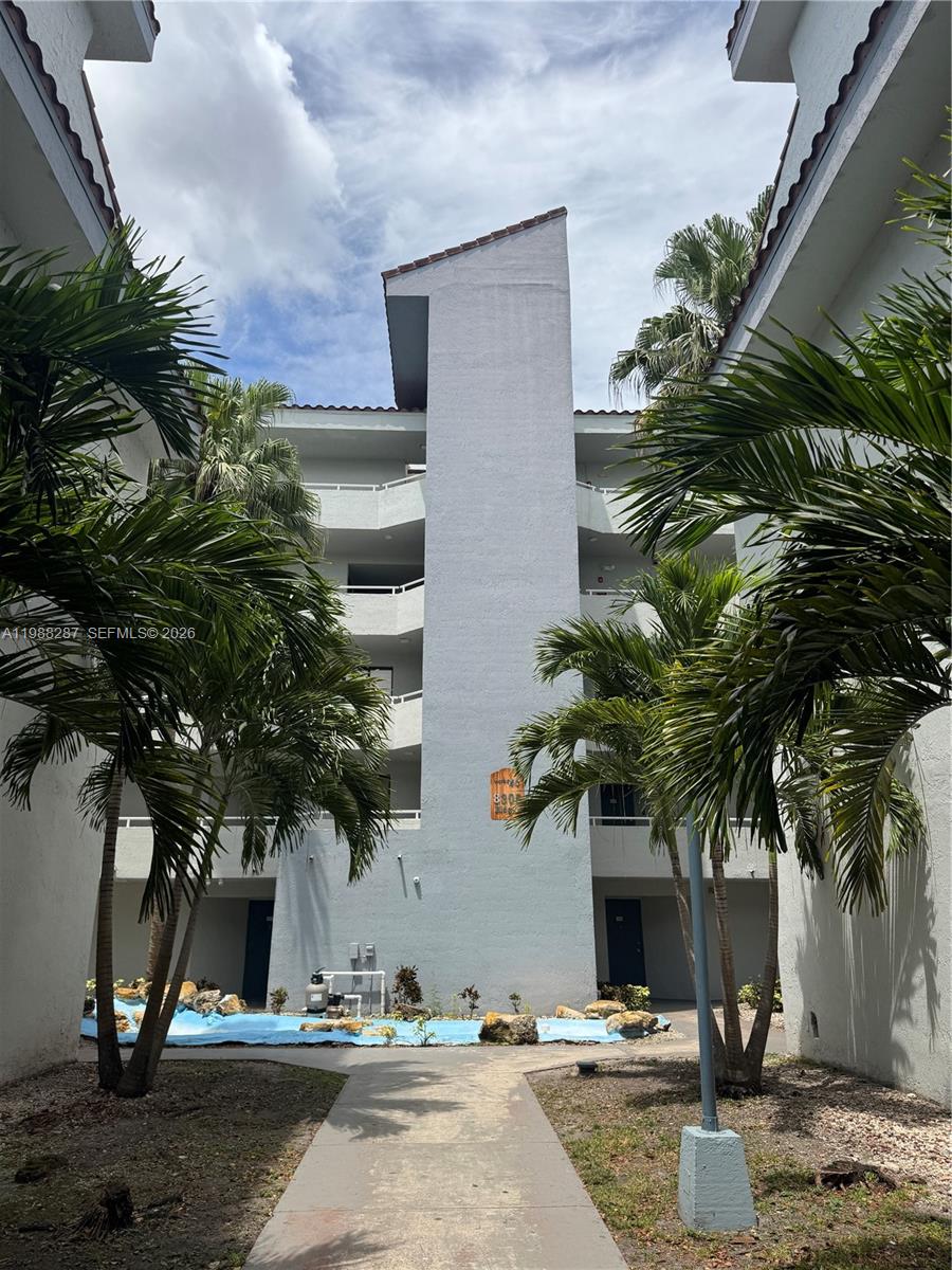 A multi-story apartment building exterior features a central tower, palm trees, and a small pool — 8305 SW 152nd Ave # 201, Miami FL 33193, MIAMI, FL