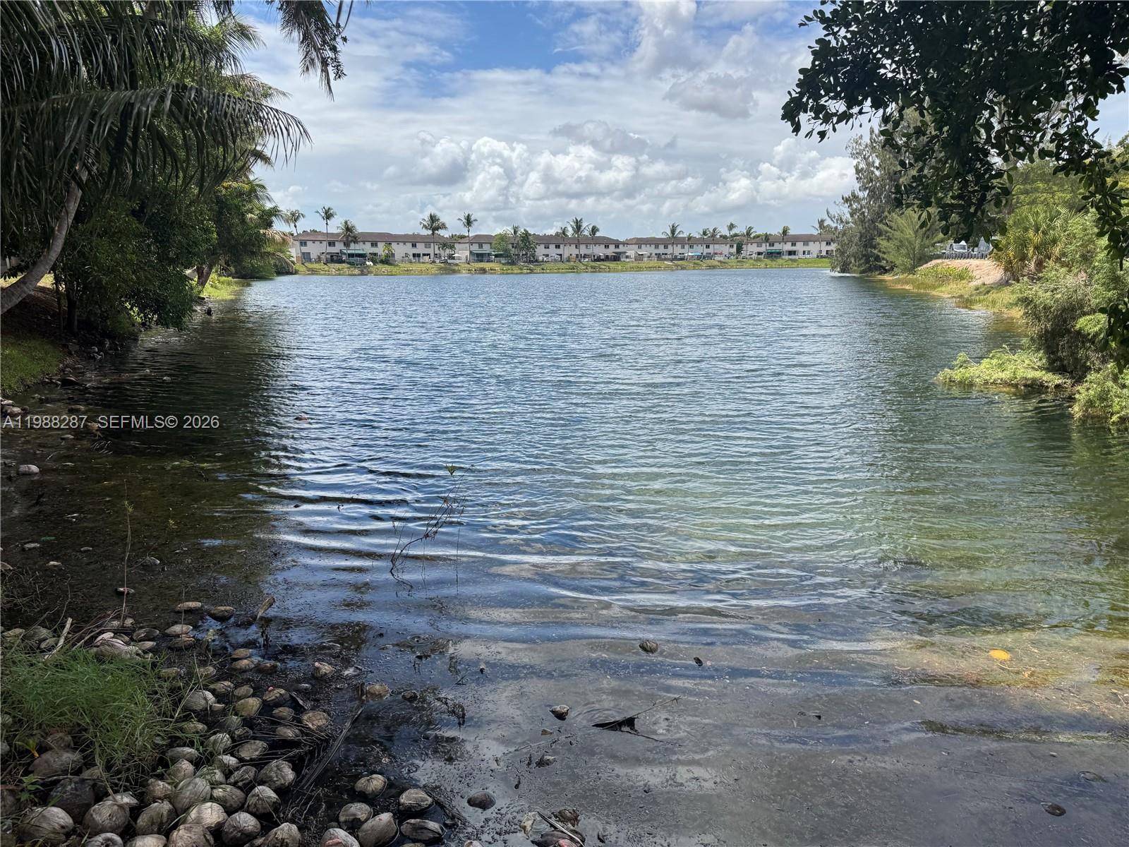 A view of a lake bordered by trees and a residential complex in the distance — 8305 SW 152nd Ave # 201, Miami FL 33193, MIAMI, FL